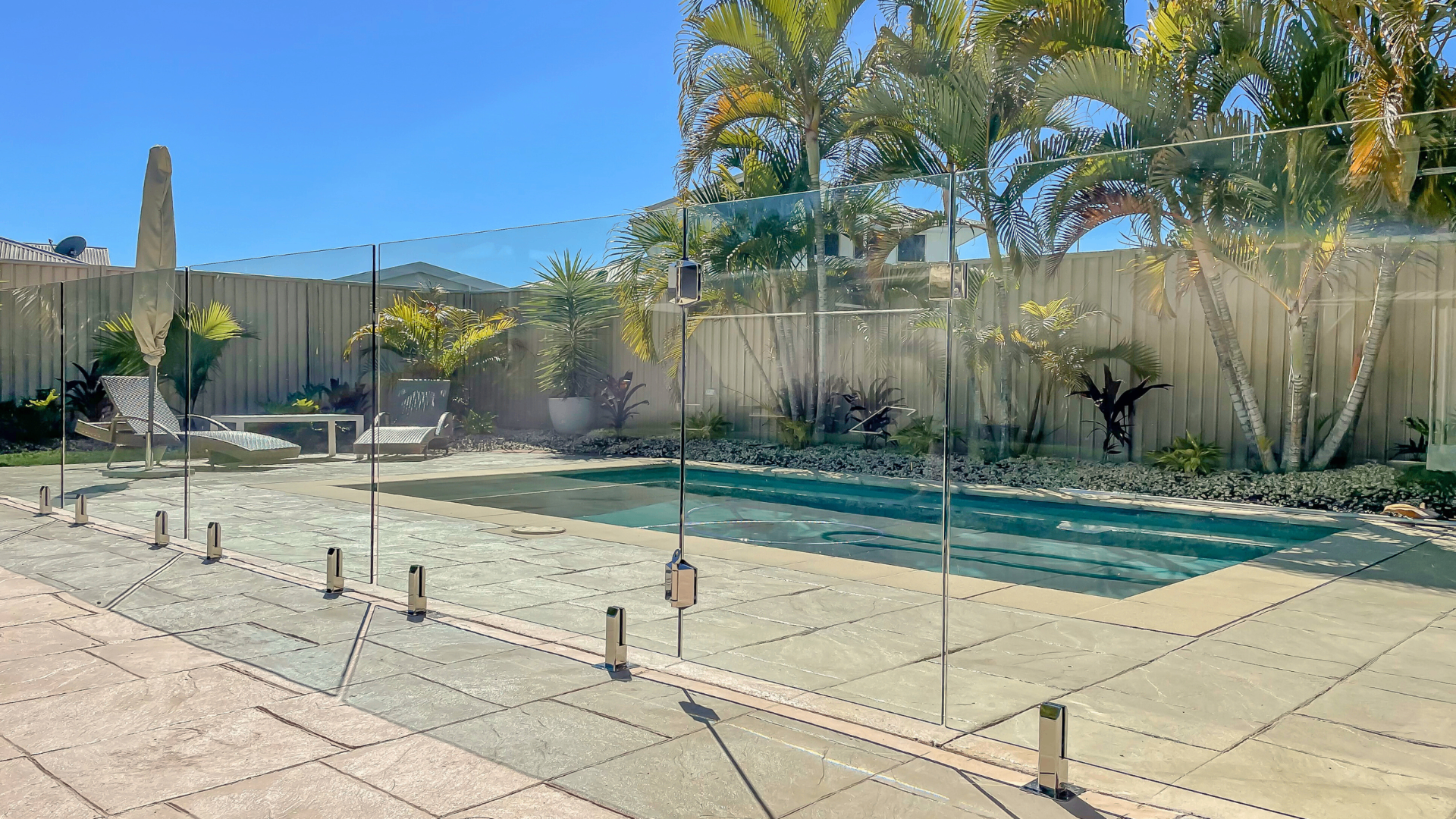 Frameless glass pool fence with tropical palm surrounds